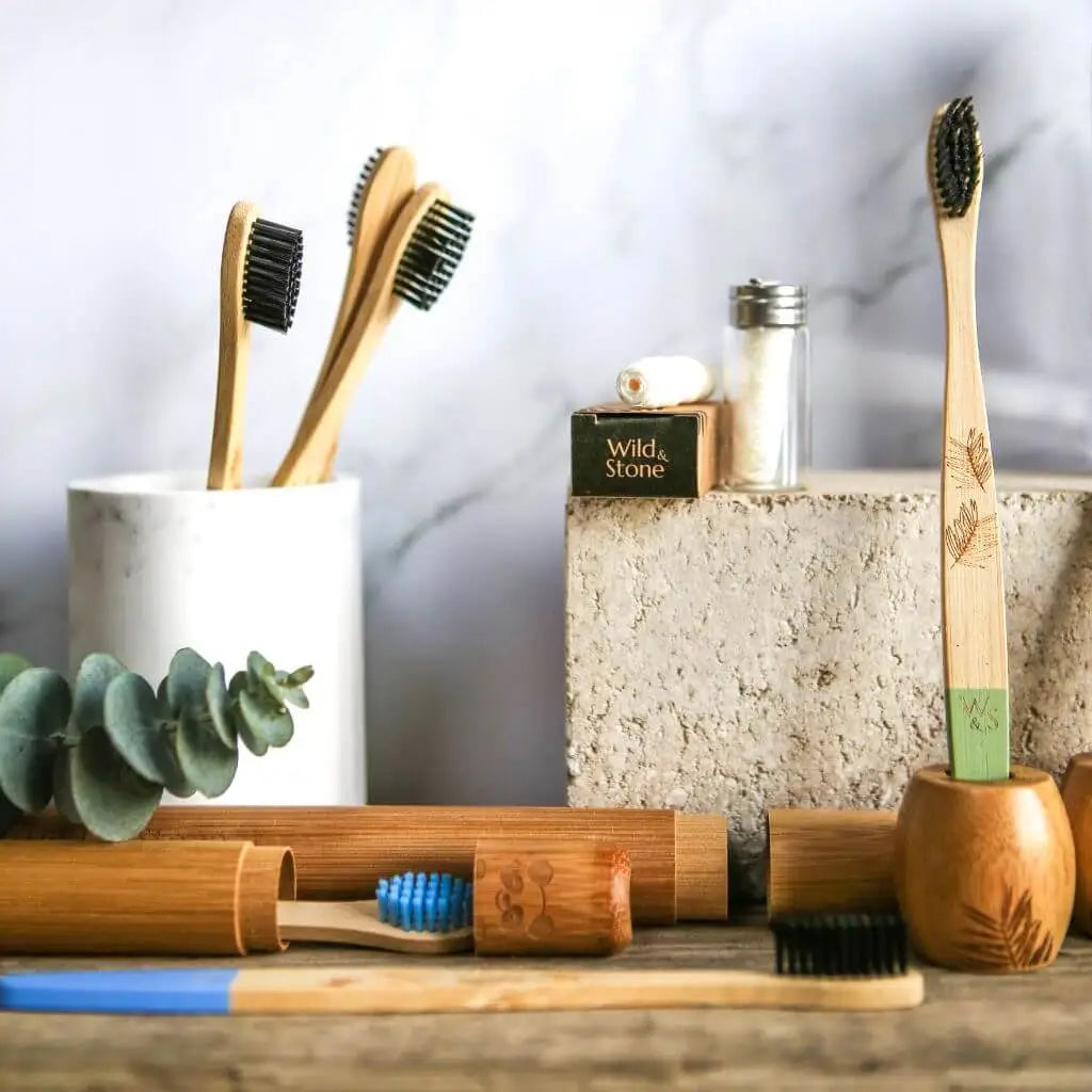 Bamboo toothbrushes and dental floss on wooden board with marbled background