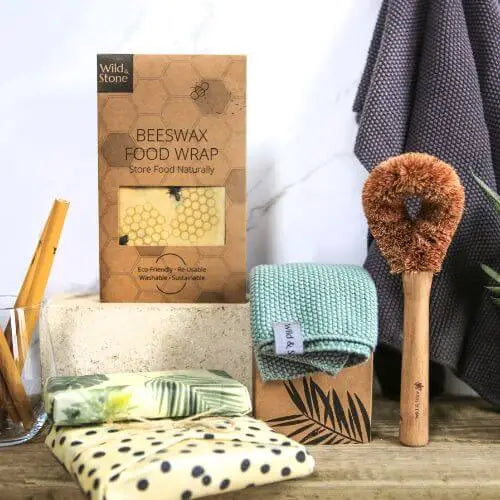Beeswax wraps, a dish brush and some bamboo straws displayed on a wooden surface