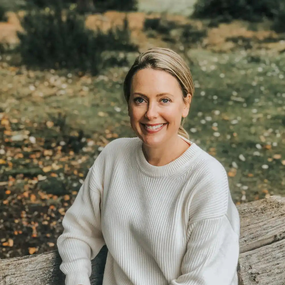 Woman wearing cream jumper sitting on bench