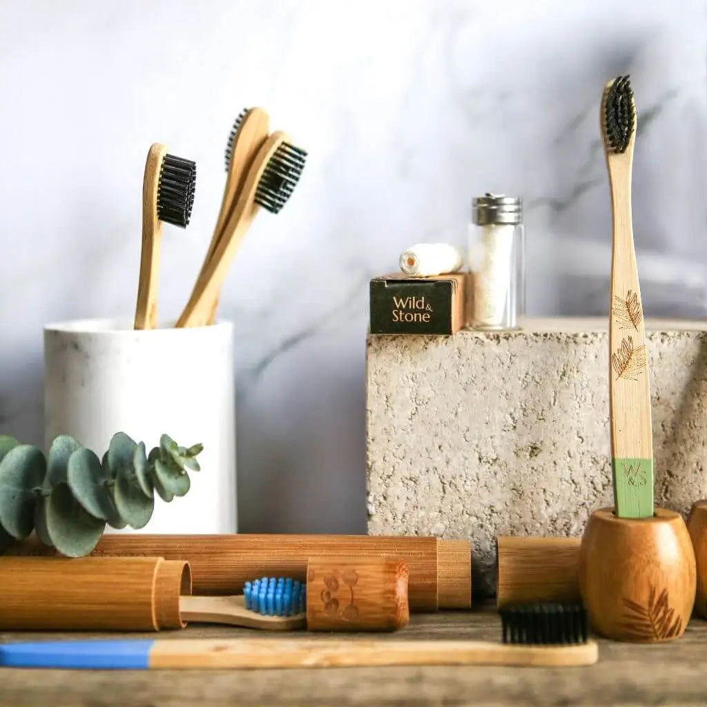 Bamboo toothbrushes and dental floss on wooden board with marbled background