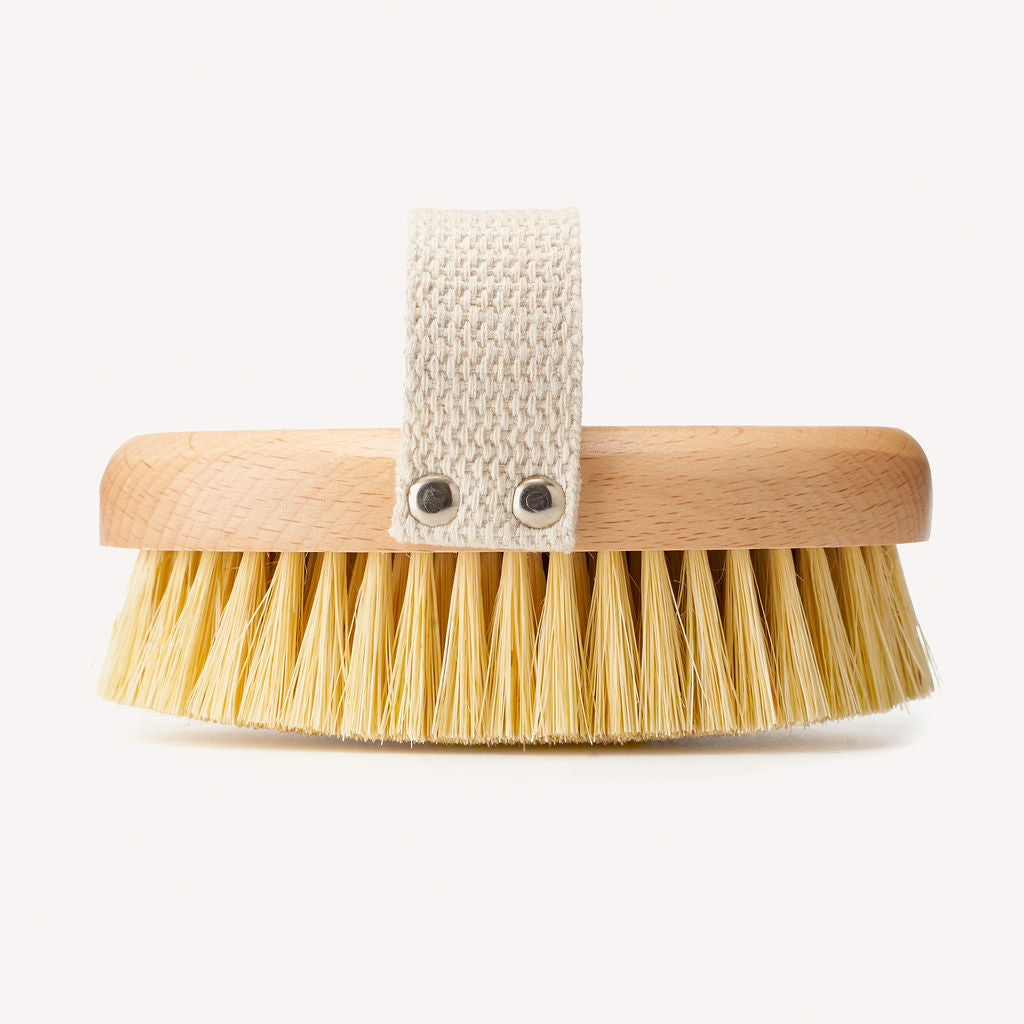 A dry body brush with natural sisal bristles and a cotton strap.